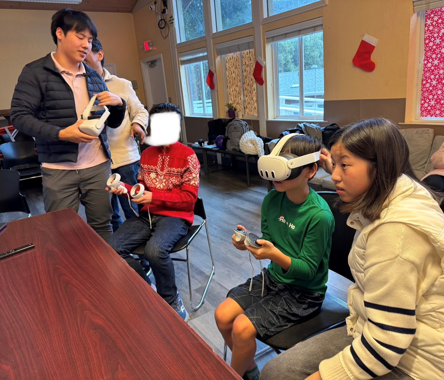 David Liu helping a child wearing a virtual reality headset during a training session in a community hall.